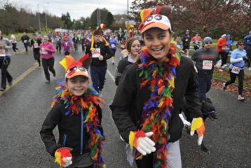 Families running in a Seattle-area Turkey Trot wearing festive Thanksgiving costumes and enjoying a community 5K event.