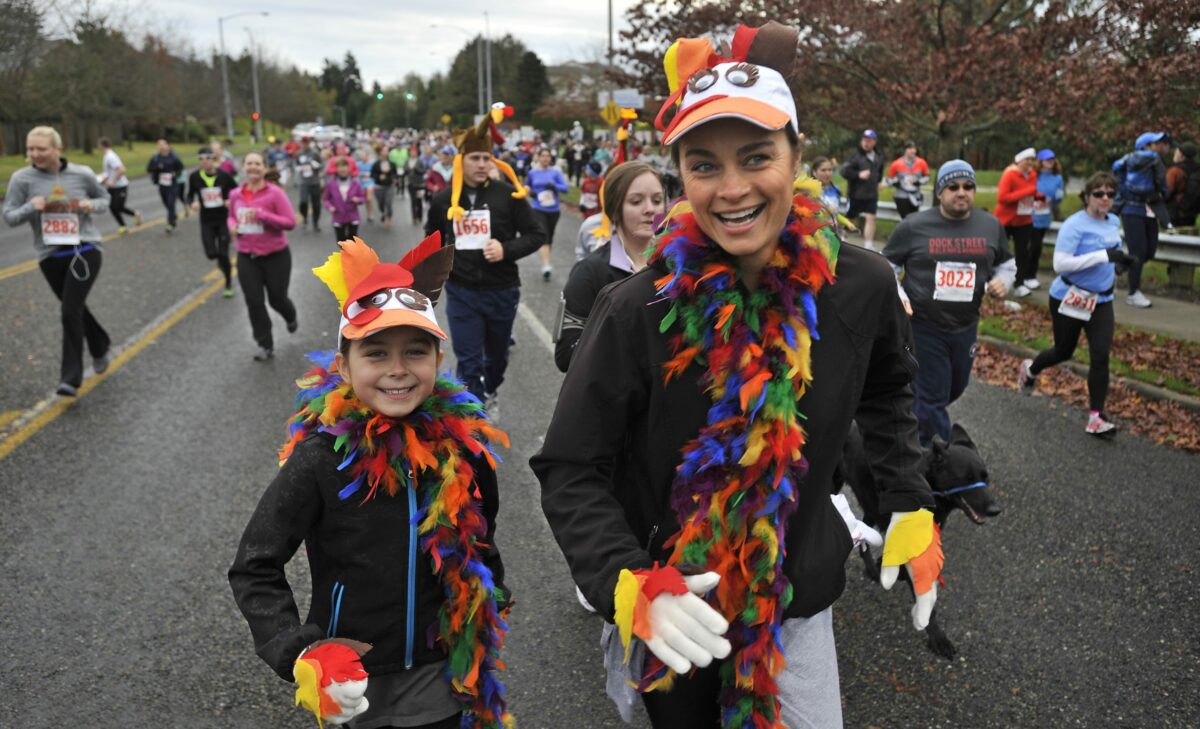 Families running in a Seattle-area Turkey Trot wearing festive Thanksgiving costumes and enjoying a community 5K event.