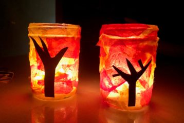 Mason jar fall tree luminaries glowing with orange and red tissue paper.