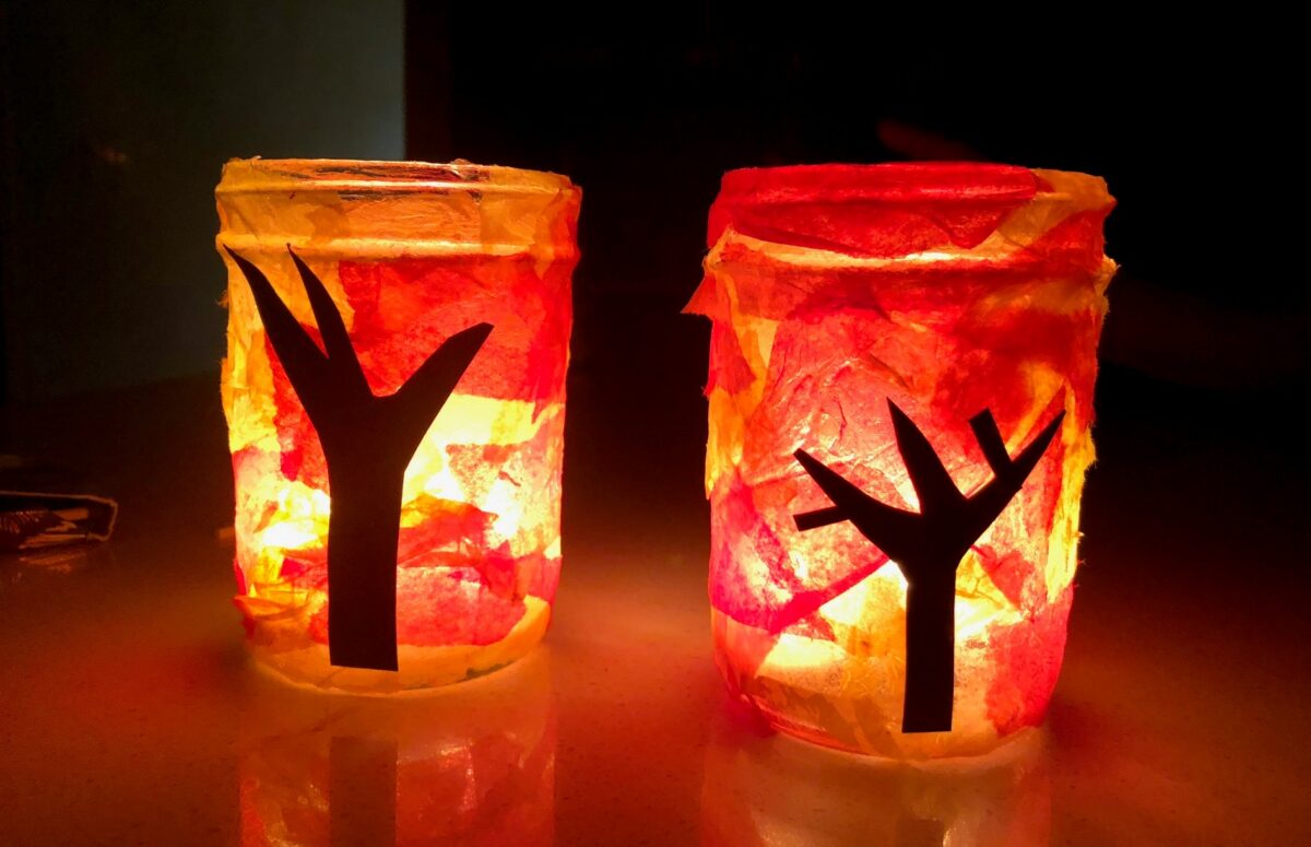Mason jar fall tree luminaries glowing with orange and red tissue paper.