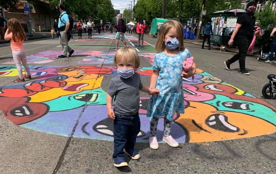 two kids in masks standing on street mural