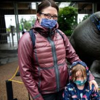 Woman and child wearing masks in front of zoo