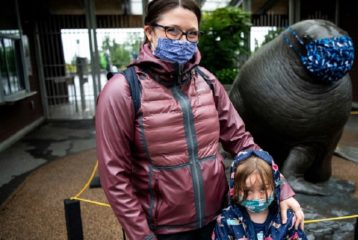 Woman and child wearing masks in front of zoo