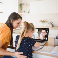 COVID-19 parents: Mother patting daughter on the back, while daughter is on a Zoom call