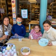 Pottery painting: An adult and three kids show off their creations at the Paint The Town outdoor table