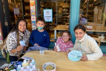 Pottery painting: An adult and three kids show off their creations at the Paint The Town outdoor table