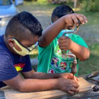 Day trip: boy helps his younger brother with a hand drill