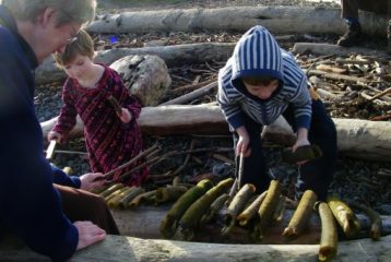 Play outside: grandmother watches two kids play with a xylophone made of kelp