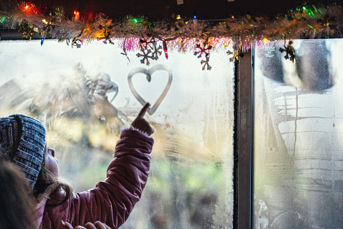 Erika's weekend picks: a girl in a winter coat and hat, drawing a heart in the fogged up window of a train car