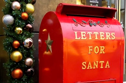 A festive Santa mailbox shines among holiday lights in a decorated neighborhood — one of several places families can drop off letters to the North Pole.