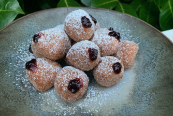 Plate of mini sufganiyot — powdered sugar–coated Hanukkah jelly doughnuts inspired by Sadie Davis-Suskind’s family recipe.