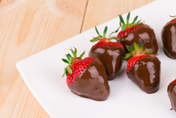 Four chocolate dipped strawberries on a plate