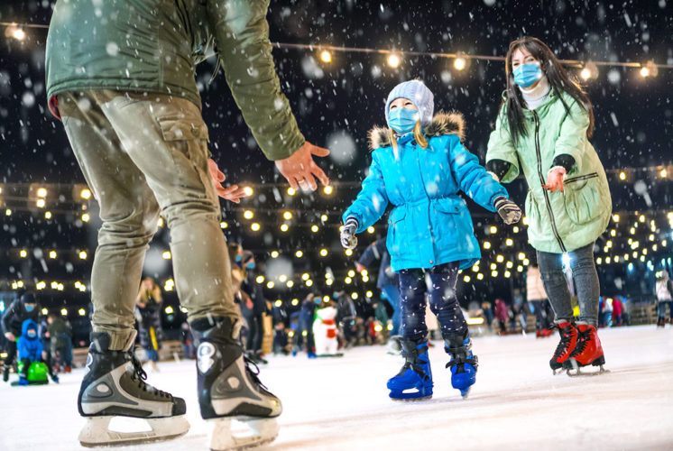 Family teaching a girl to ice skate