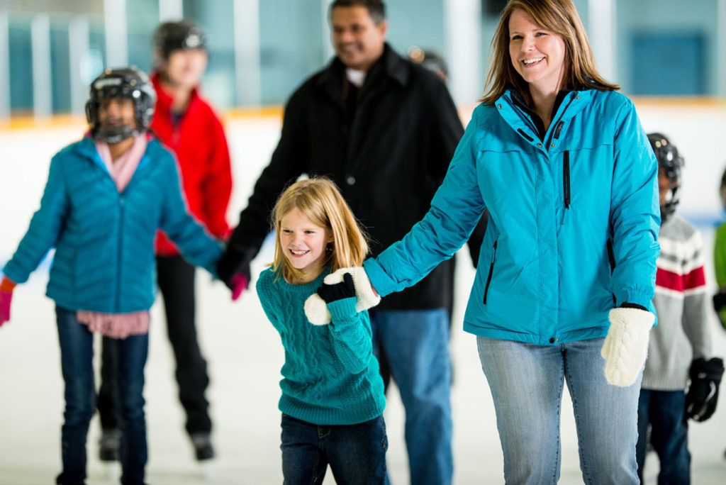 Woman and girl ice skating in winter clothes