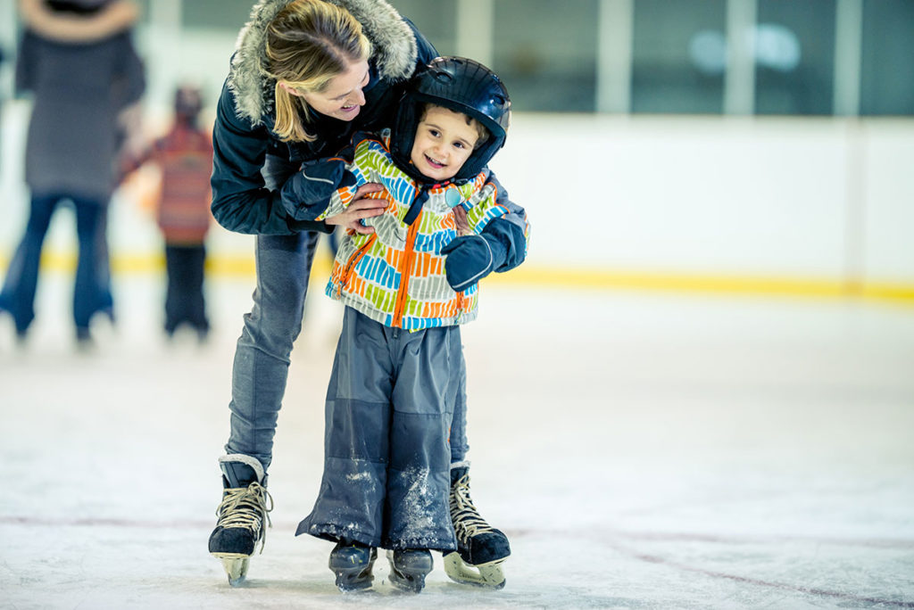 Boy wearing helmet while learning to ice skate