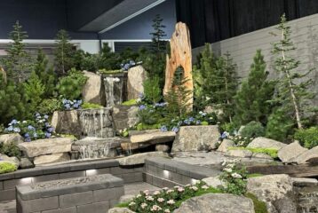 Stone slabs create a set with a waterfall, trees, and flowers at the Flower and Garden Festival in Seattle.
