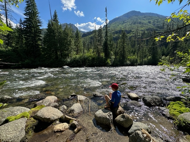 Boy sitting on a river at a state park in Washington.