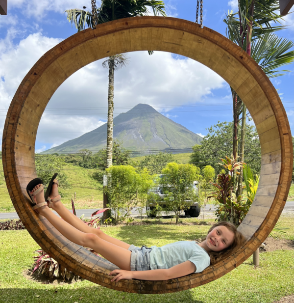 A child is lying down in a circular seat with an amazing view in the background. Travel for neurodiverse children may be tiring, give space and designate a place and time to rest.