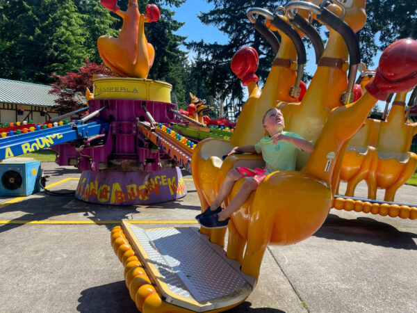 Little boy on a theme park ride waiting to be buckled in.