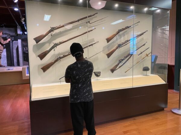 An exhibit hosts many rifles in a case at the Lewis Army Museum
