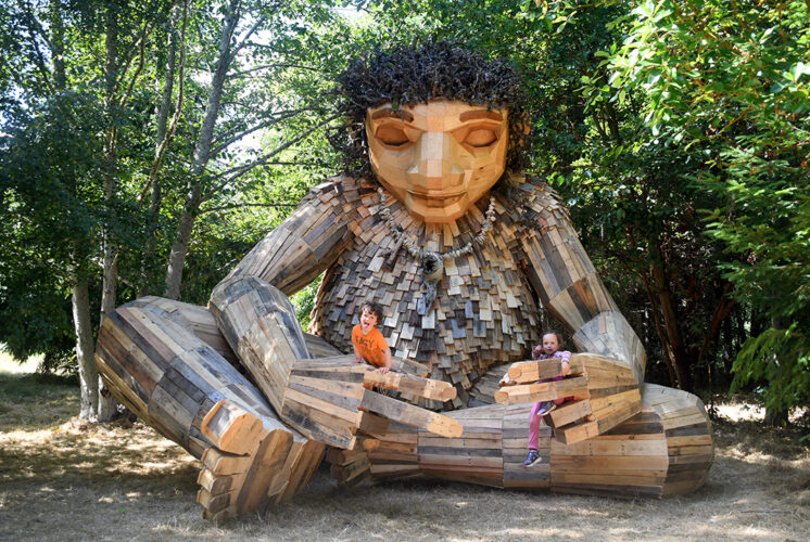 Giant troll sculpture Pia the Peacekeeper sitting cross-legged with arms outstretched, located in Sakai Park on Bainbridge Island, part of the Northwest Trolls project.