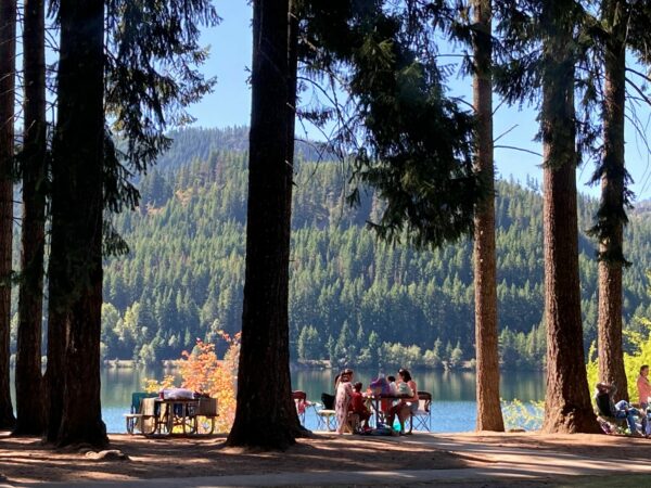 Family seated at picnic tables in front of the lake at Lake Easton State Park.