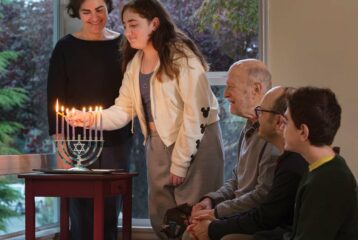 A Seattle family lighting the Chanukah menorah together, with children watching the candles glow during the Festival of Lights.