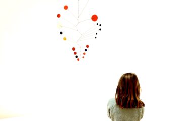 Calder mobiles in primary colors capture the attention of Cora, age 7. Photo by Elizabeth Hunter