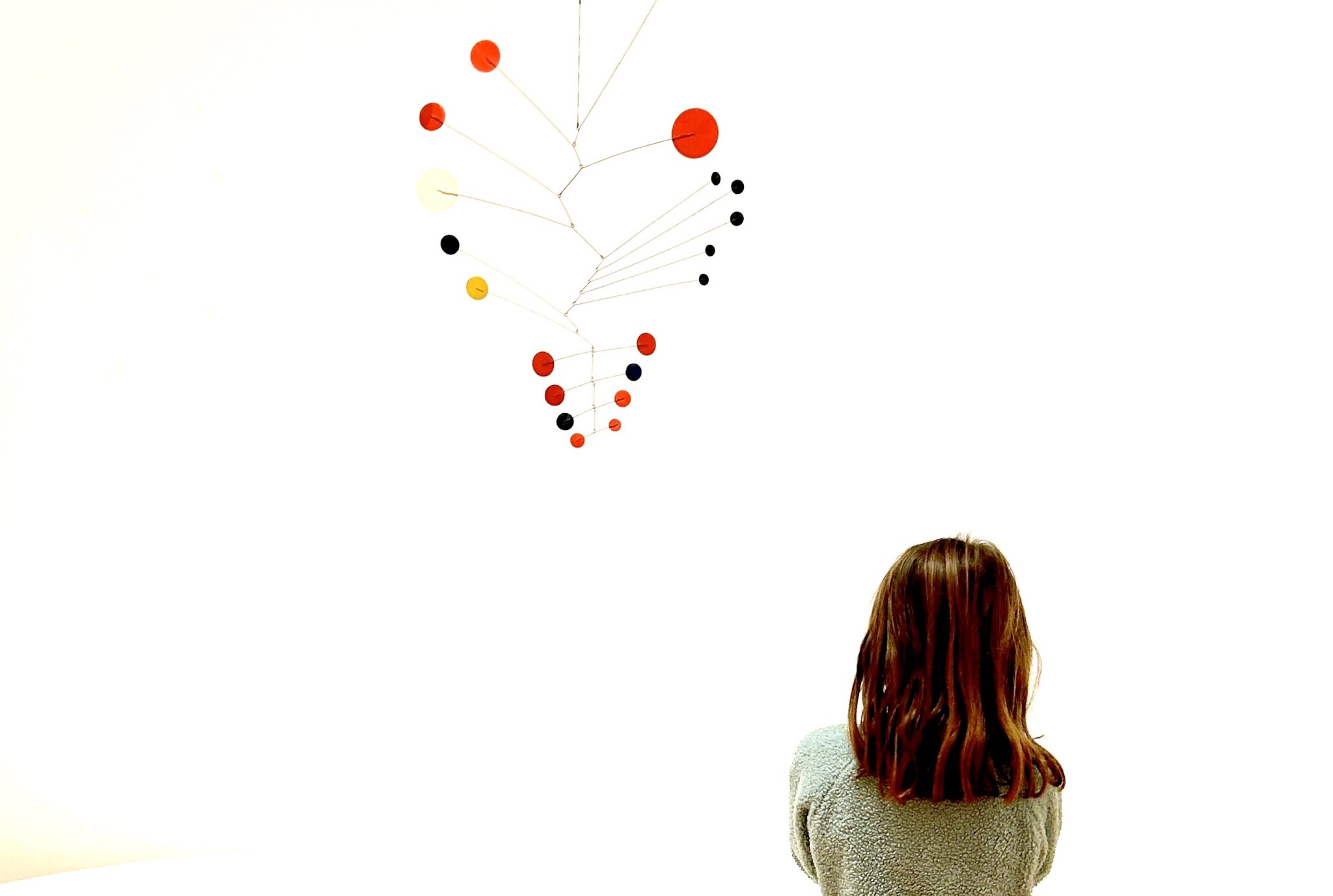 Calder mobiles in primary colors capture the attention of Cora, age 7. Photo by Elizabeth Hunter