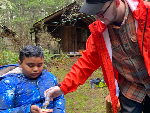 A tour guide squeezes a drop of syrup onto a cracker for the taste test.