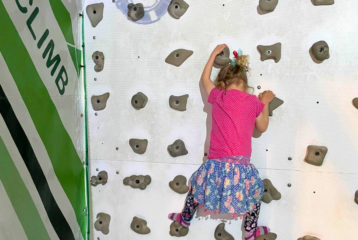 Little girl halfway up a climbing wall