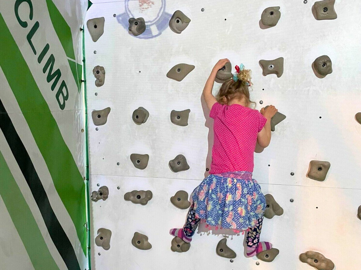 Little girl halfway up a climbing wall