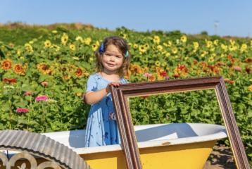 Two children posing with sunflowers and festival food at a Washington farm