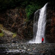 Franklin Falls in with Jonathan Gulingan standing in the foreground. The waterfall is full and crashing into the rocks.