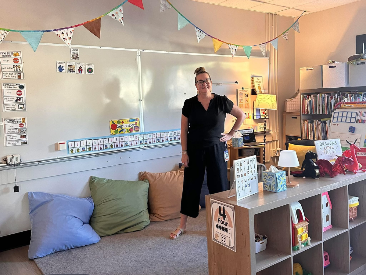 Woman stands in front of white board in children's classroom.