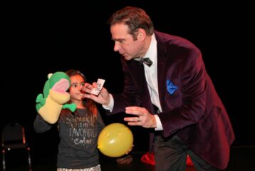 Magician and child hold puppet for trick.