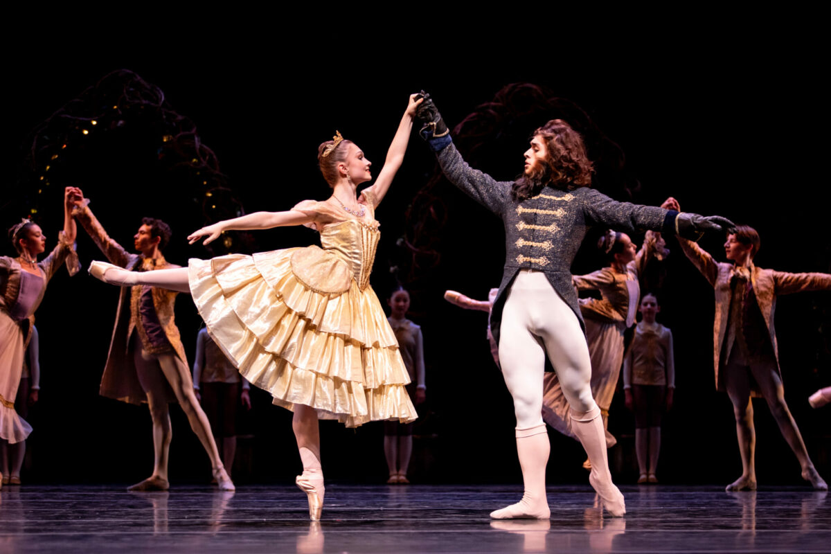 Female dancer holds hands with dancer dressed as a Beast