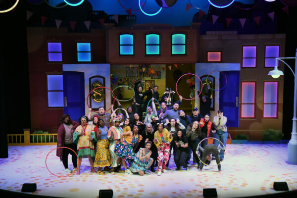 Entire cast, holding hula hoops, post on stage. 