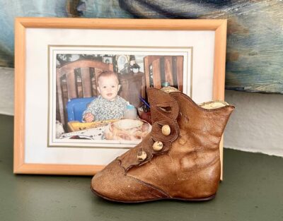 Worn old brown leather baby boot next to picture frame of baby