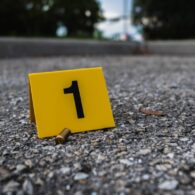 A group of yellow crime scene evidence markers on the street after a gun shooting brass bullet shell casing rifle