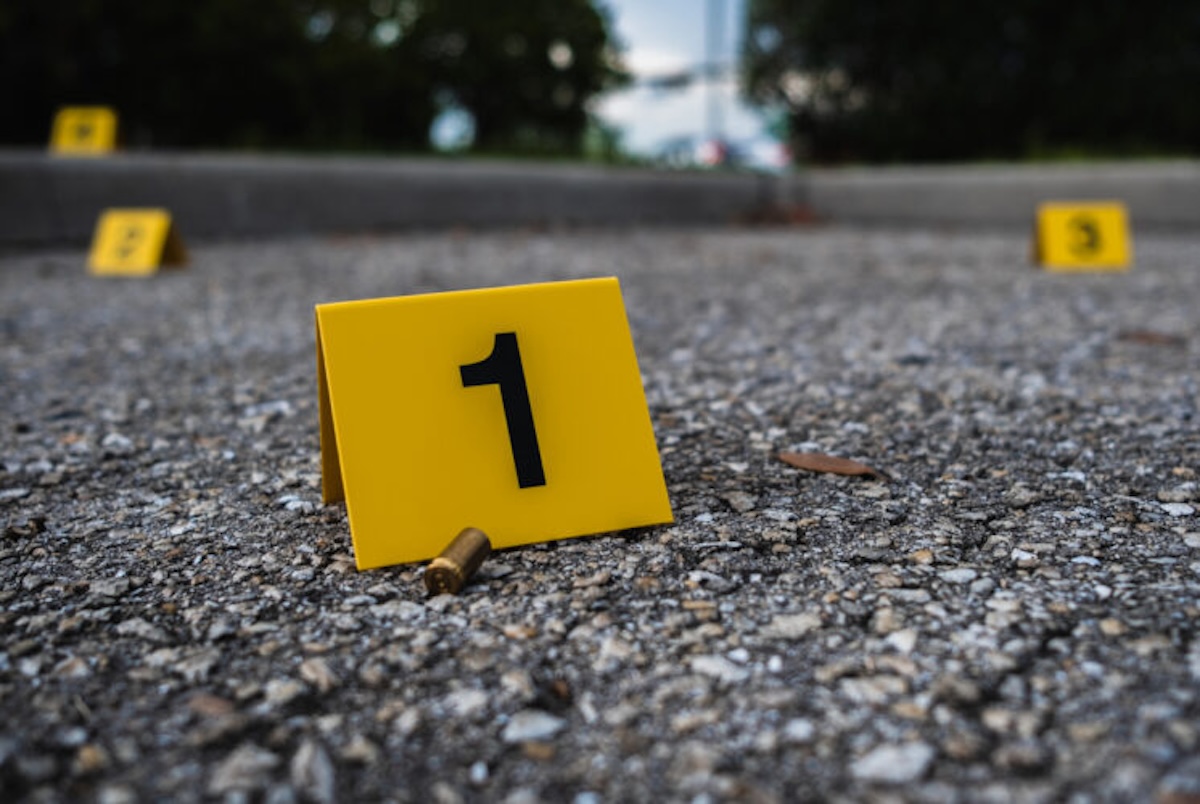 A group of yellow crime scene evidence markers on the street after a gun shooting brass bullet shell casing rifle