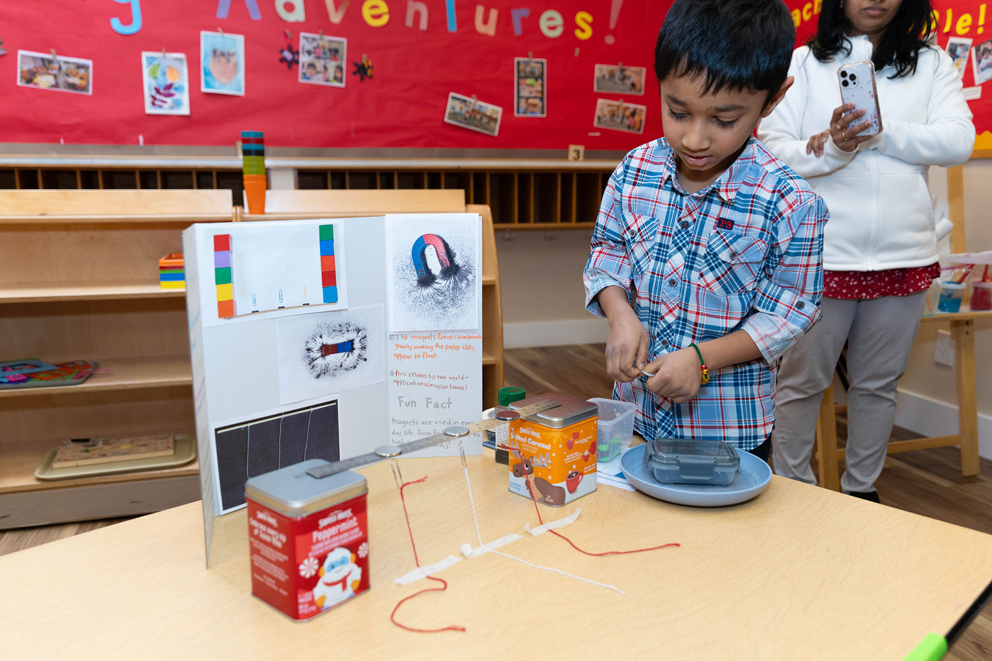 Elementary age child at Montessori school demonstrating his science fair project on a table