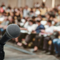 Microphone over the Abstract blurred photo of conference hall or seminar room with attendee background