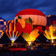 Four huge hot air balloons, glowing from lights within against a night sky