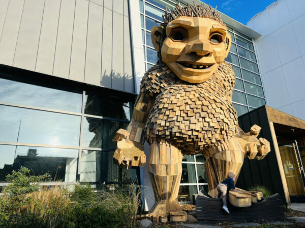 Frankie Feetsplinter troll sculpture standing beside the National Nordic Museum in Ballard, blending recycled wood and modern urban surroundings.