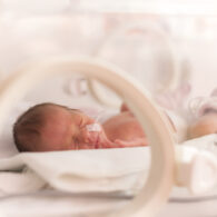 Newborn baby lying in a hospital NICU bed with monitoring equipment
