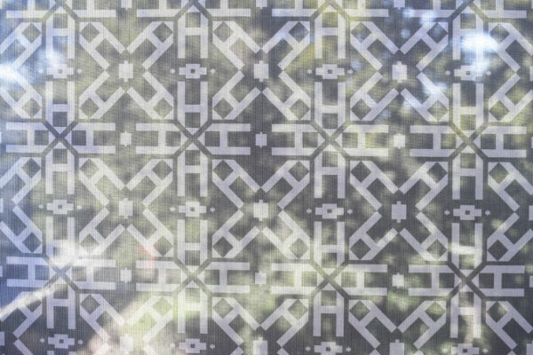 Closeup of the patterned scrim at the Geometry of Light exhibit, featuring repeating A’s.