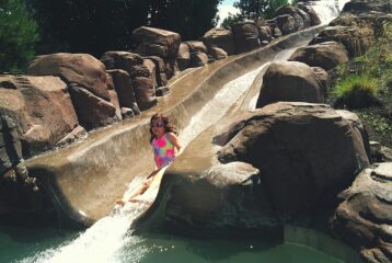 Kid splashing into pool after water slide ride at Sunriver Resort