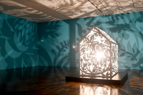 Visitors walking through a dimly lit room filled with shadow projections at the Seattle Asian Art Museum.