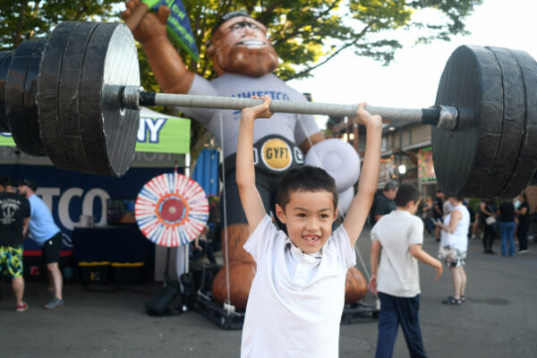 Child lifting toy barbells at a kids activity station at the Washington State Fair